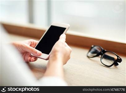 business, technology and people concept - close up of woman texting on smartphone