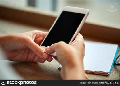 business, technology and people concept - close up of woman texting on smartphone