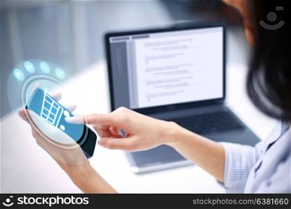 business, technology and people concept - close up of woman with shopping cart projection over smartphone screen at office. close up of woman with shopping cart on smartphone