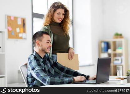 business, technology and people concept - happy creative team with laptop computer working at office. creative team with laptop working at office. creative team with laptop working at office