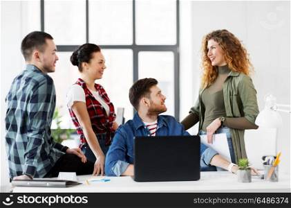 business, technology and people concept - happy creative team with laptop computer working at office. creative team with laptop working at office. creative team with laptop working at office