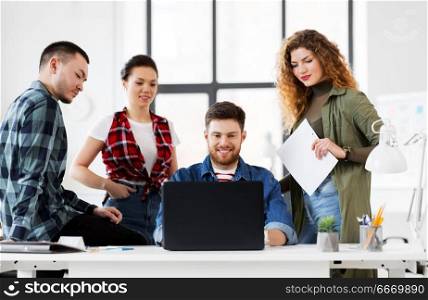 business, technology and people concept - happy creative team with laptop computer working at office. creative team with laptop working at office. creative team with laptop working at office