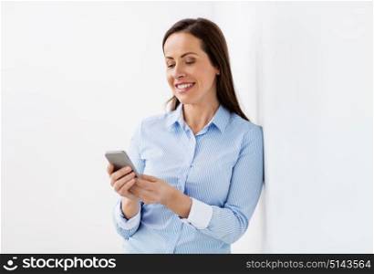 business, technology and people concept - happy smiling businesswoman with smartphone at office. happy businesswoman with smartphone at office