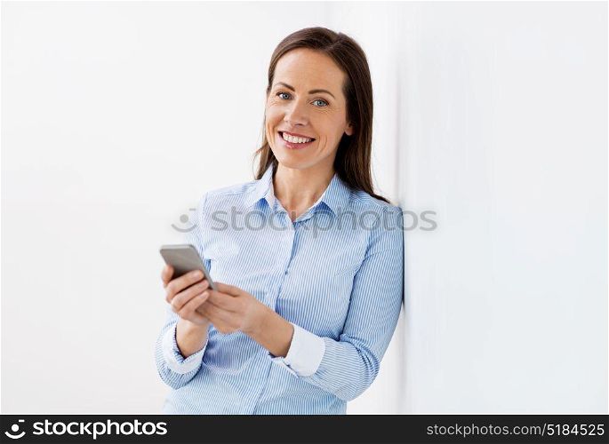 business, technology and people concept - happy smiling businesswoman with smartphone at office. happy businesswoman with smartphone at office