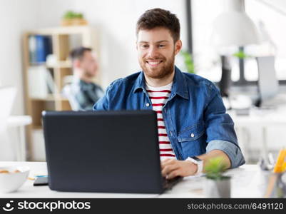 business, technology and people concept - happy smiling creative man with laptop computer working at office. smiling creative man with laptop working at office. smiling creative man with laptop working at office