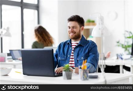 business, technology and people concept - happy smiling creative man with laptop computer working at office. smiling creative man with laptop working at office. smiling creative man with laptop working at office