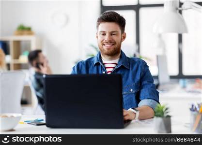 business, technology and people concept - happy smiling creative man with laptop computer working at office. smiling creative man with laptop working at office