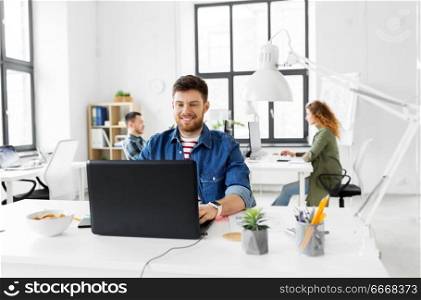 business, technology and people concept - happy smiling creative man with laptop computer working at office. smiling creative man with laptop working at office. smiling creative man with laptop working at office