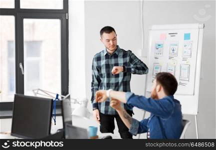 business, technology and people concept - man showing smart watch to creative team at office presentation. man showing smart watch to creative team at office. man showing smart watch to creative team at office