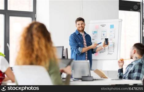 business, technology and people concept - man showing smartphone user interface design to creative team at office presentation. man showing smartphone user interface at office. man showing smartphone user interface at office