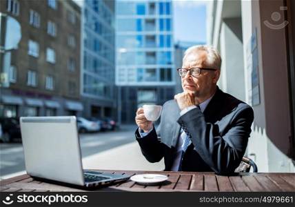 business, technology and people concept - senior businessman with laptop computer drinking coffee at city street cafe. senior businessman with laptop drinking coffee