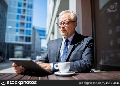 business, technology and people concept - senior businessman with tablet pc computer drinking coffee at city street cafe. senior businessman with tablet pc drinking coffee