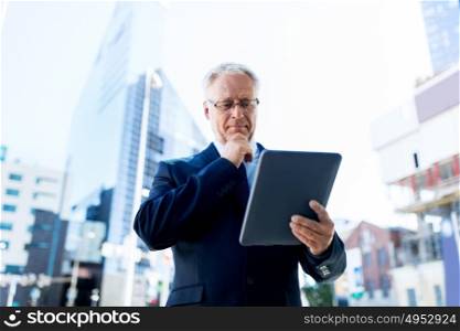 business, technology and people concept - senior businessman with tablet pc computer on city street. senior businessman with tablet pc on city street