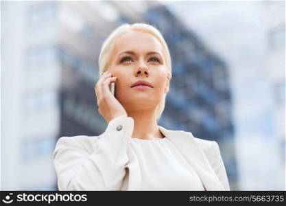 business, technology and people concept - serious businesswoman with smartphone talking over office building