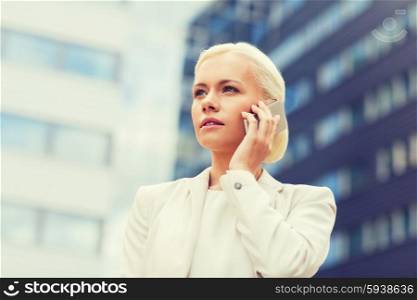 business, technology and people concept - serious businesswoman with smartphone talking over office building