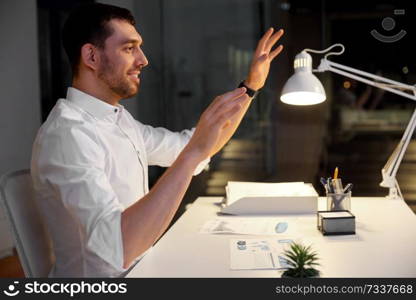 business, technology and people concept - smiling businessman using gestures at night office. businessman using gestures at night office