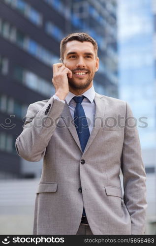 business, technology and people concept - smiling businessman with smartphone talking over office building