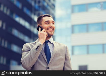 business, technology and people concept - smiling businessman with smartphone talking over office building