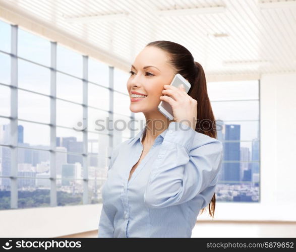 business, technology and people concept - smiling businesswoman calling on smartphone over office room or new apartment background