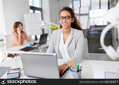business, technology and people concept - smiling businesswoman in glasses with laptop computer working at office. happy businesswoman with laptop working at office. happy businesswoman with laptop working at office