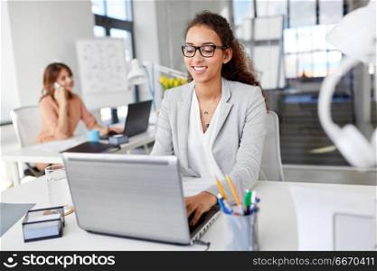 business, technology and people concept - smiling businesswoman in glasses with laptop computer working at office. happy businesswoman with laptop working at office. happy businesswoman with laptop working at office