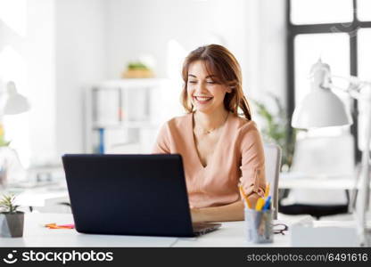 business, technology and people concept - smiling businesswoman with laptop computer working at office. happy businesswoman with laptop working at office. happy businesswoman with laptop working at office