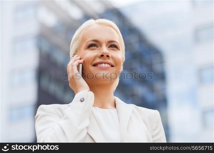 business, technology and people concept - smiling businesswoman with smartphone talking over office building