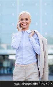 business, technology and people concept - smiling businesswoman with smartphone talking over office building