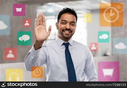 business, technology and people concept - smiling indian businessman making high five gesture with app icons on virtual screen over office background. indian businessman making high five gesture