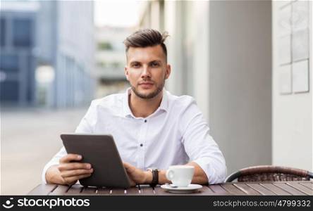 business, technology and people concept - young man with tablet pc computer and coffee cup at city street cafe