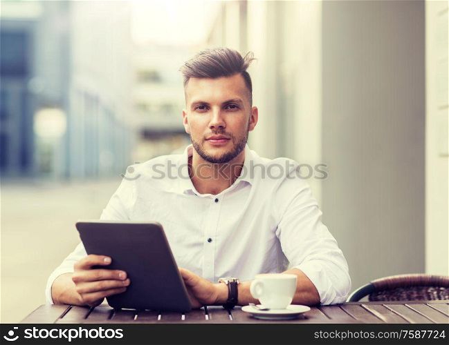 business, technology and people concept - young man with tablet pc computer and coffee cup at city street cafe. man with tablet pc and coffee at city cafe