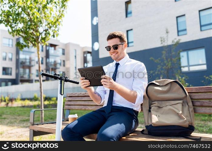 business, technology and people concept - young smiling businessman with tablet computer, backpack and electric scooter sitting on street bench in city. businessman with tablet computer, bag and scooter