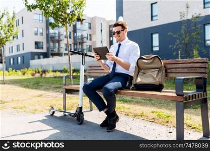business, technology and people concept - young smiling businessman with tablet computer, backpack and electric scooter sitting on street bench in city. businessman with tablet computer, bag and scooter