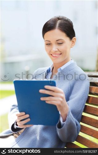 business, technology and people concept - young smiling woman with tablet pc computer sitting on bench in city