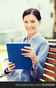 business, technology and people concept - young smiling woman with tablet pc computer sitting on bench in city