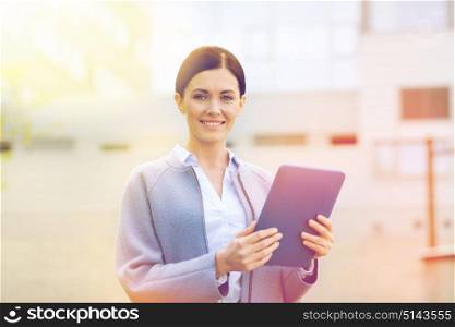 business, technology and people concept - young smiling woman with tablet pc computer over office building. smiling business woman with tablet pc in city