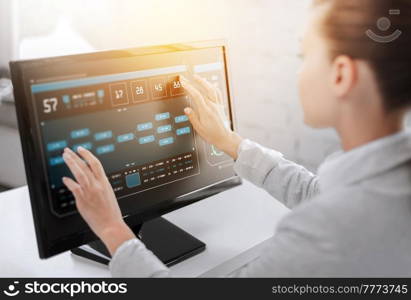 business, technology and programming concept - businesswoman working with virtual data on touchscreen of computer monitor at office. businesswoman with virtual data on computer screen