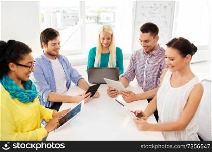 business, technology and startup concept - happy creative team with table pc computer at office. creative team with table computers in office