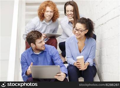 business, technology and startup concept - smiling creative team with laptop and tablet pc computer sitting on staircase