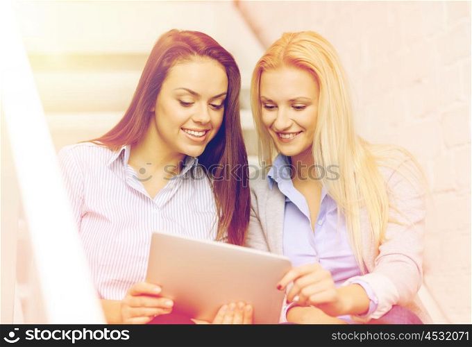 business, technology and startup concept - smiling creative team with tablet pc computer sitting on staircase