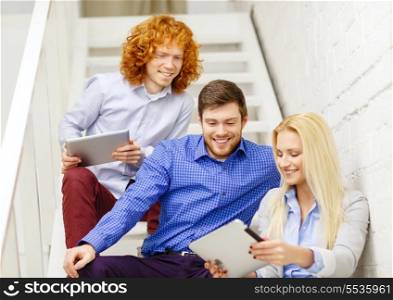 business, technology and startup concept - smiling creative team with tablet pc computer sitting on staircase