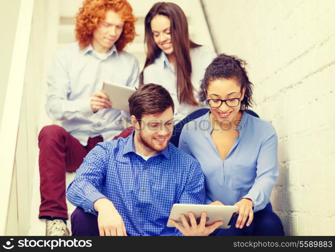 business, technology and startup concept - smiling creative team with tablet pc computer sitting on staircase