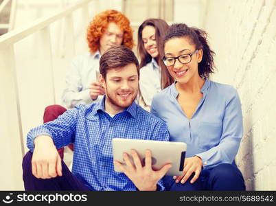 business, technology and startup concept - smiling creative team with tablet pc computer sitting on staircase