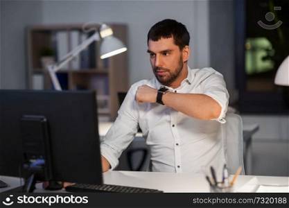 business, technology and time management concept - businessman using voice command recorder on smart watch at nigh office. businessman using voice command on smart watch