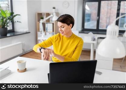 business, technology and time management concept - happy smiling businesswoman using smart watch at office. happy businesswoman using smart watch at office