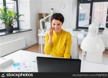 business, technology and ui design concept - smiling creative woman with laptop computer and user interface templates calling on smartphone at office. happy ui designer calling on smartphone at office