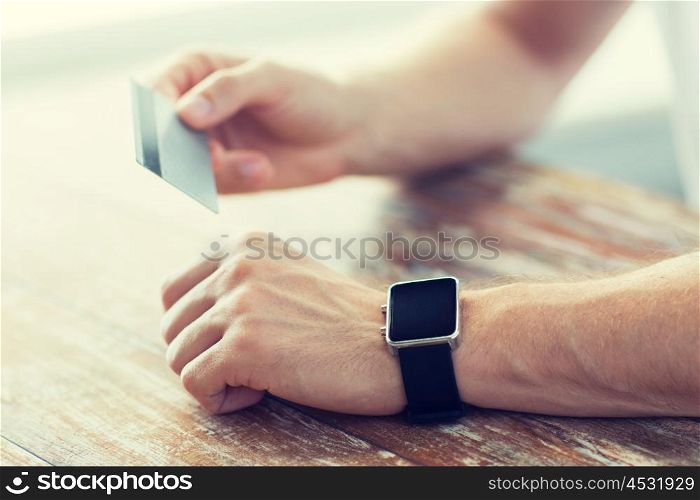 business, technology, cash free and internet people concept - close up of male hands with smart watch and credit card at office