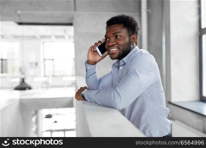 business, technology, communication and people concept - african american businessman calling on smartphone at office. businessman calling on smartphone at office