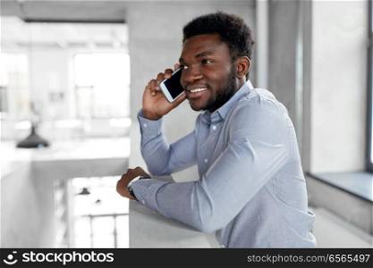 business, technology, communication and people concept - african american businessman calling on smartphone at office. businessman calling on smartphone at office