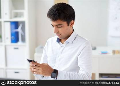 business, technology, communication and people concept - businessman with smartphone at office. businessman with smartphone at office